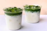 Two glasses of iced doze. matcha latte, layered green matcha over milk with ice