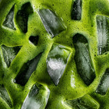 Close-up of vivid green iced matcha with ice cubes and a fine layer of foam