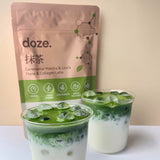 A prepared doze. matcha latte beside the pouch, showing the blend's naturally vivid green colour