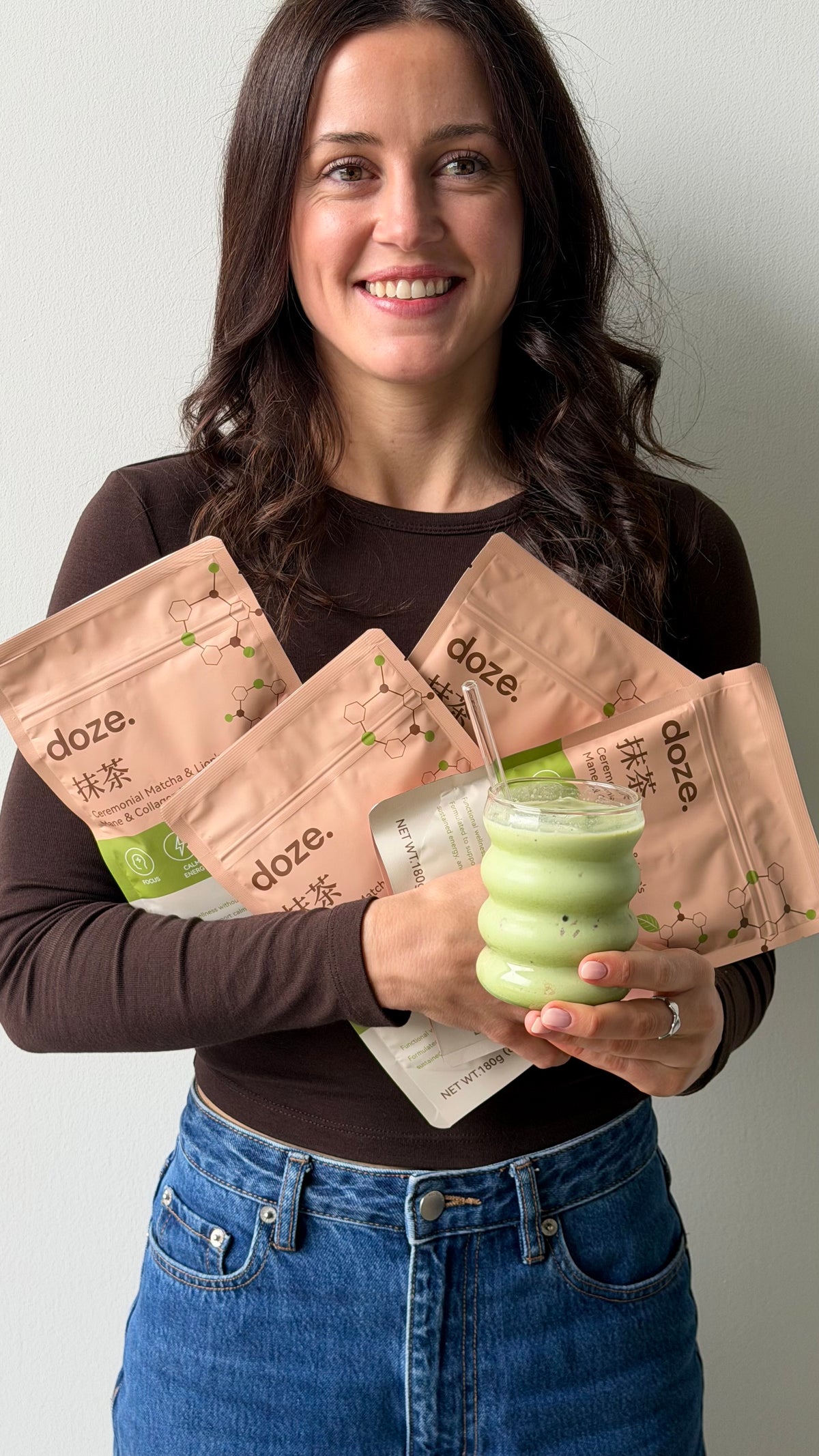 Holding four doze. matcha pouches and an iced matcha latte